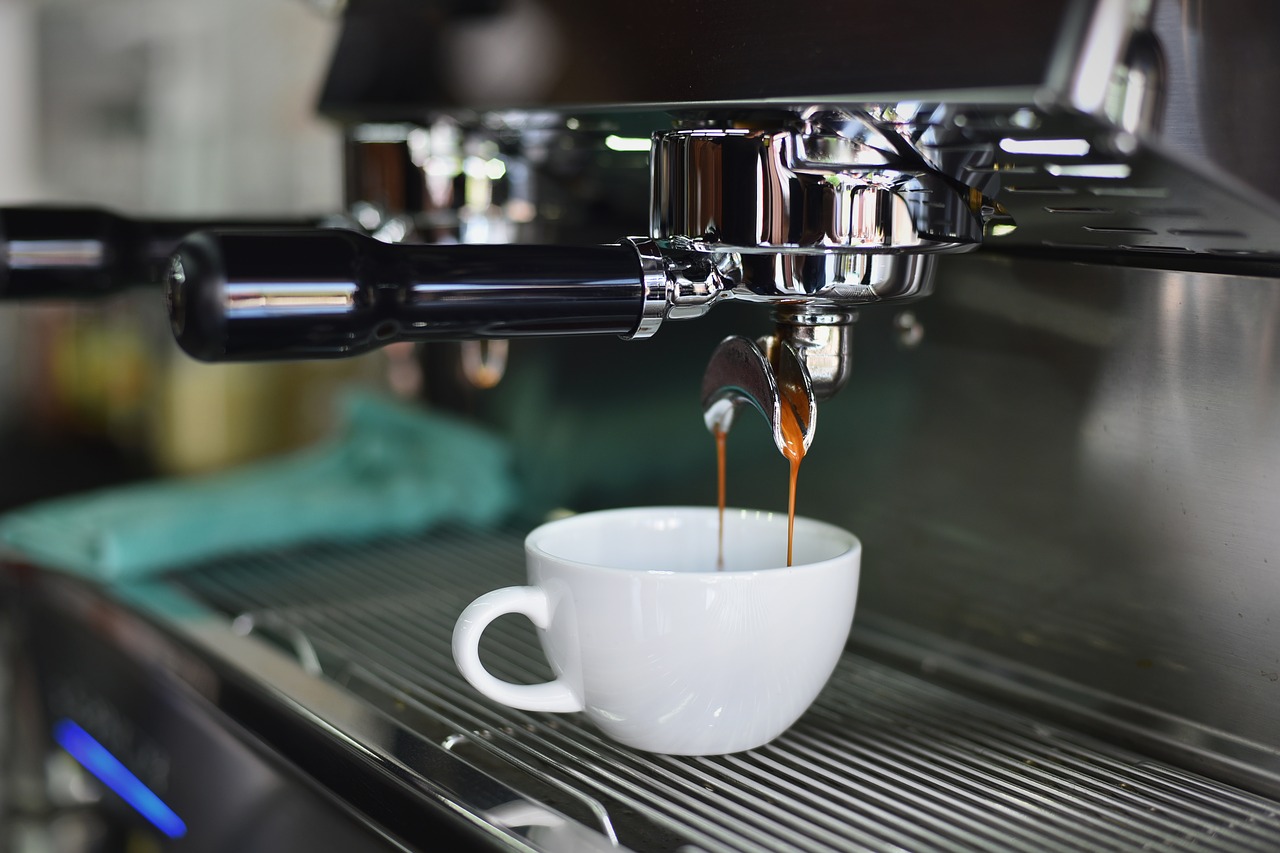 Frisch gekochter Kaffer läuft aus der Maschine in eine weiße Tasse.
